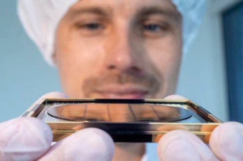 Ein Mitarbeiter von Q.ant zeigt einen Wafer, aus dem photonische Chips geschnitten werden
